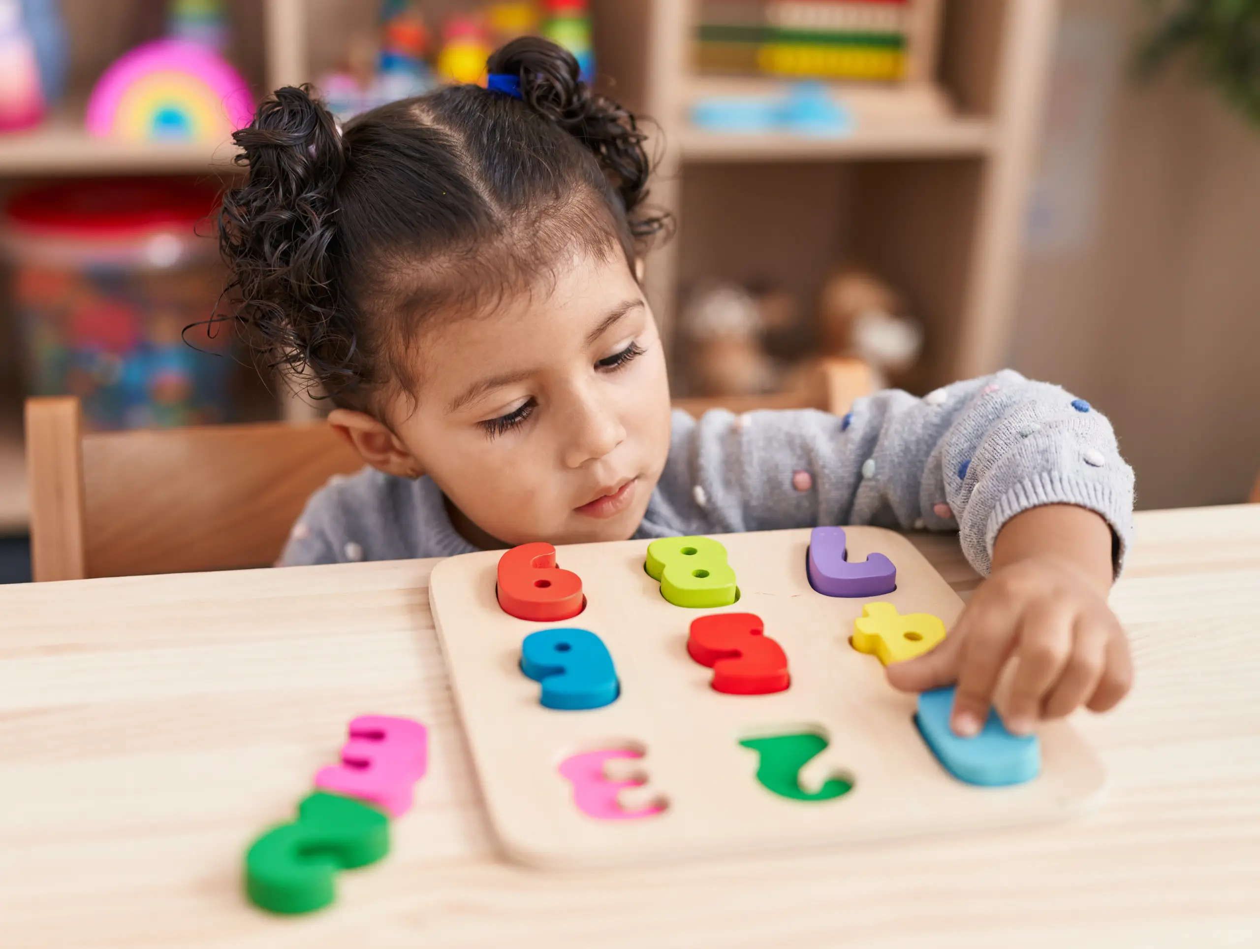 Criança pequena brincando com números coloridos em atividade educativa que estimula o desenvolvimento infantil na educação infantil.