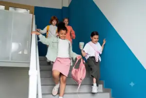 Crianças descem a escada da escola com mochilas após as atividades, ilustrando a rotina da escola ampliada e a permanência estendida no ambiente escolar.