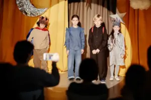 Crianças fantasiadas participam de apresentação de teatro escolar em palco, estimulando criatividade, comunicação e trabalho em equipe.